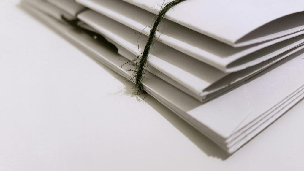 Pile of white envelopes tied with a green string, showcasing a minimalist design.