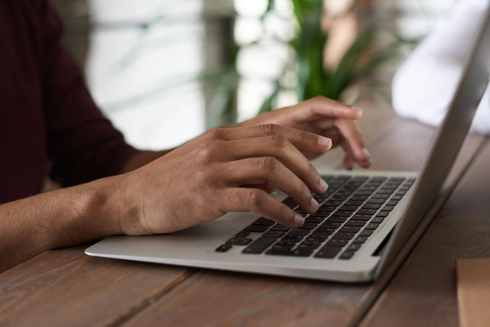 Hands of a person typing on a laptop keyboard indoors, ideal for remote work and freelancing themes.